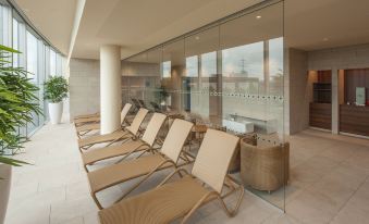 a row of beige chairs lined up against a wall in front of a large window at Four Points by Sheraton Panoramahaus Dornbirn