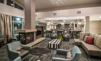 a modern hotel lobby with comfortable seating , a fireplace , and a large chandelier , creating a welcoming atmosphere at Residence Inn Rapid City