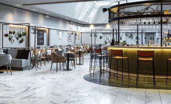 a modern restaurant with marble floors , a bar area , and a dining table with chairs at Radisson Blu Scandinavia Hotel, Aarhus