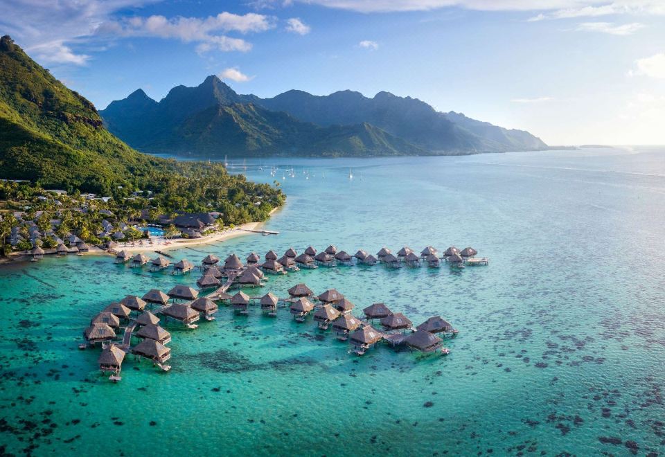 aerial view of a tropical island with overwater bungalows , surrounded by clear blue water and lush green mountains at Hilton Moorea Lagoon Resort and Spa