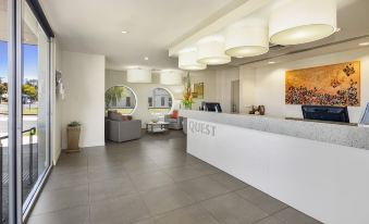 "a modern hotel lobby with white walls , gray tiles , and a reception desk labeled "" quest .""." at Quest Mildura