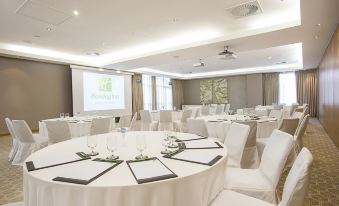 a large conference room set up for a meeting , with multiple round tables and chairs arranged in a semicircle at Holiday Inn Mauritius Mon Tresor