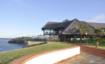 a large house with a thatched roof and a view of the ocean in the background at Sea Cliff Hotel