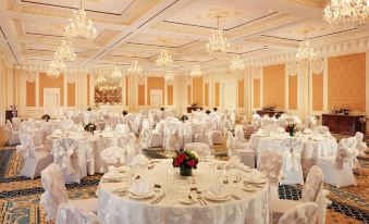 a large banquet hall filled with white tablecloths , chairs , and multiple dining tables set for a formal event at Fairmont Grand Hotel - Kyiv