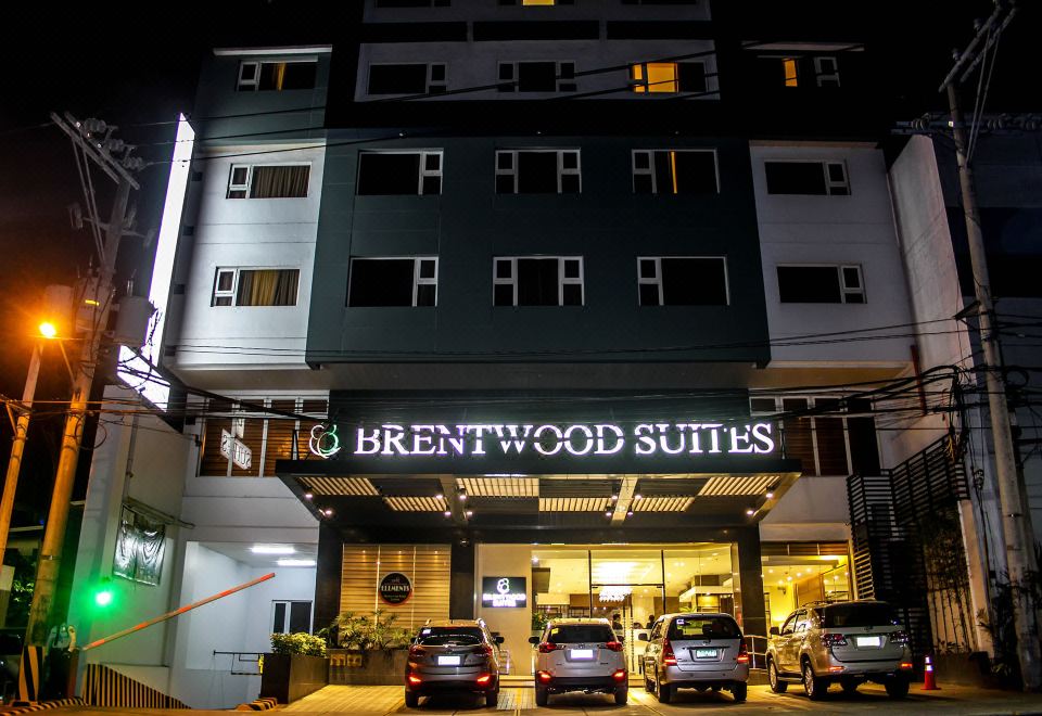 "the exterior of a large building with the name "" brentwood suites "" lit up at night" at Brentwood Suites