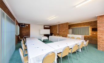 a large conference room with a long table , chairs , and a projector screen at the front at Thurgoona Country Club Resort