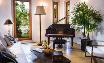 a living room with a grand piano , a coffee table , and several potted plants placed around it at Eraeliya Villas & Gardens