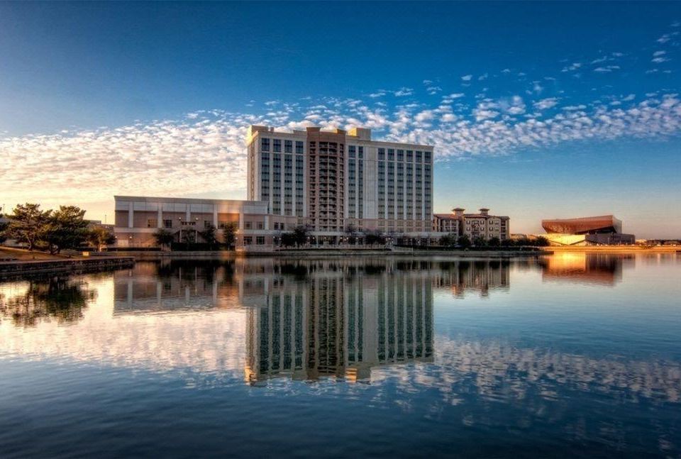 a large building with a clear blue sky reflected in the water , surrounded by water at Marriott Dallas Las Colinas