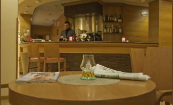 a person is sitting at a table with a magazine and a glass of wine at City Hotel