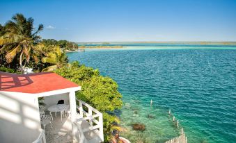 a beautiful view of a lake , with a white building overlooking the water and trees in the background at Hotel Laguna Bacalar