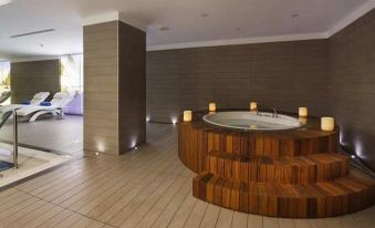 a modern bathroom with wooden floors and a large circular bathtub surrounded by candles , creating a cozy and inviting atmosphere at DoubleTree by Hilton Istanbul-Avcilar