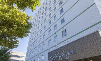 a tall white building with multiple floors , possibly a hotel or office building , situated on a city street at Comfort Hotel Koriyama