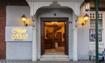 The entrance to a restaurant features an ornate door with a sign above it indicating its affiliation with a hotel at Mom Hotel