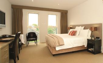 a spacious bedroom with a large bed , a dining table , and a window overlooking the ocean at Brooklands of Mornington