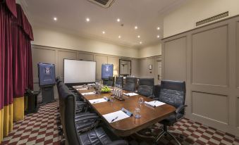 a conference room with a large table surrounded by chairs and a screen on the wall at Macdonald Bath Spa Hotel