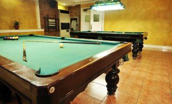 a room with multiple pool tables , each equipped with a cue stick and pool balls at Executive Hotel
