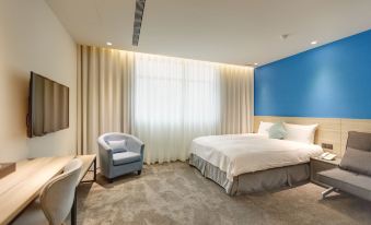 a modern hotel room with a large bed , a couch , and a tv , all situated in a minimalist style at Hub Hotel