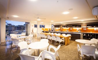 a modern , well - lit restaurant with white chairs and tables arranged in a semi - circle around the dining area at The Island Accommodation