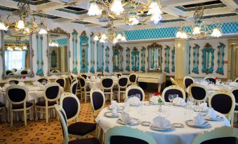 a large dining room with white tables and chairs , blue and white walls , and chandeliers hanging from the ceiling at Hotel Roman by Dumbrava