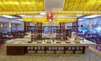 a large dining room with a long wooden table , multiple chairs , and a variety of dishes and utensils at Emeralda Resort Ninh Binh