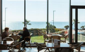 a person is sitting in a restaurant with a large window overlooking the ocean , looking out at the view at Hotel Flamingo