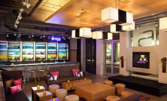 a modern lounge area with a large window and multiple couches , chairs , and a bar at Aloft Chesapeake