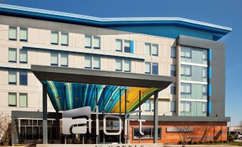 a large hotel with a colorful mural on the side , surrounded by a parking lot at Aloft Chesapeake