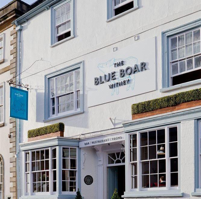 "a building with the sign "" the blue boar hotel "" on it , located in a small town" at The Blue Boar