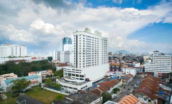 an aerial view of a large white building with multiple floors and a tall tower , surrounded by other buildings in the background at Cititel Penang