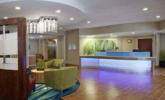 a modern hotel lobby with a reception desk , couches , and a chandelier , creating an inviting atmosphere for guests at SpringHill Suites Atlanta Six Flags