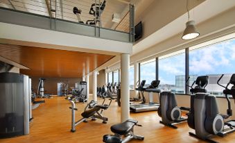 a well - equipped gym with various exercise equipment , such as treadmills , weight machines , and benches , arranged on a wooden floor at Sheraton Grand Seattle