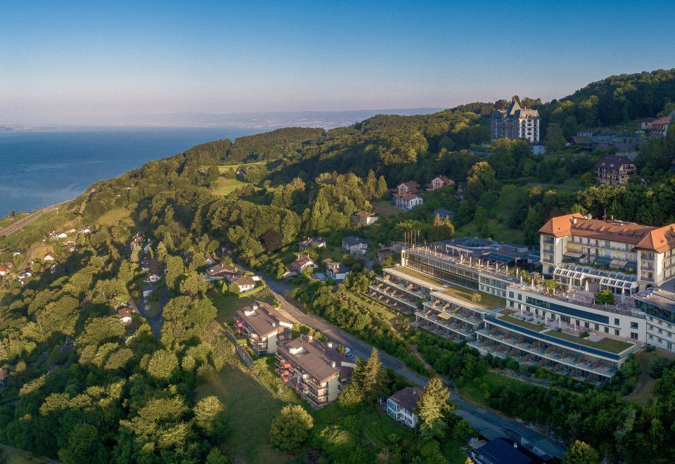 a bird 's eye view of a large building surrounded by trees and mountains , with the ocean in the background at Le Mirador Resort and Spa