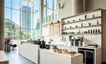 a modern coffee shop with a white counter and shelves filled with various coffee - making equipment at Civic Hotel, Autograph Collection