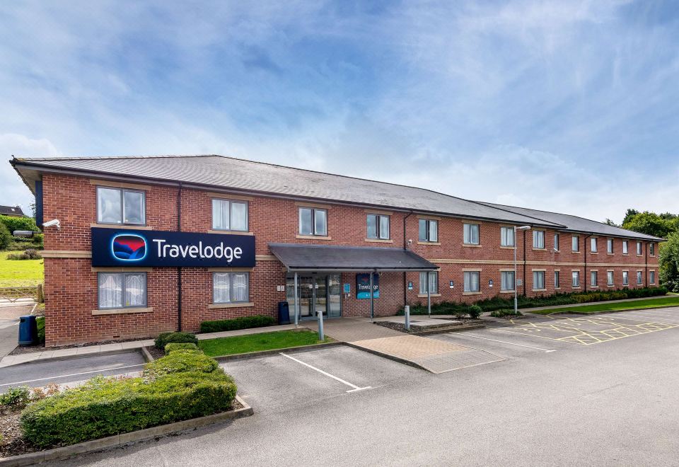 "a red brick building with a sign that reads "" travelodge "" prominently displayed on the front" at Travelodge Ashbourne