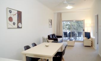 a spacious living room with a dining table and chairs , a couch , and a tv at Jacana Apartments