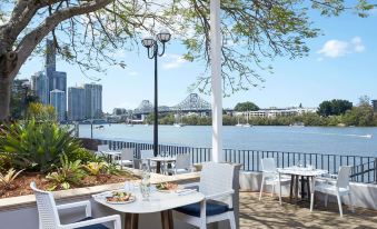 a table with a plate of food is set up on a balcony overlooking a river and cityscape at Stamford Plaza Brisbane