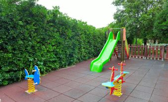 a playground with a green slide , swings , and other play equipment surrounded by greenery and trees at Nautilus