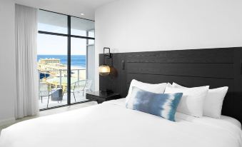a modern bedroom with a large bed and a view of the ocean through a window at Wave Resort