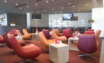 a modern lounge area with various seating options , including chairs and couches , as well as a television at Park Inn by Radisson Krakow