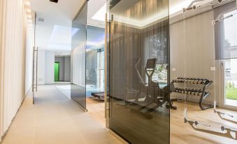 a modern gym with large glass walls , including a fitness room featuring a treadmill and other exercise equipment at Palazzo Castri 1874 Hotel & Spa