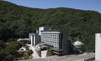 "a large building with a green dome and the word "" mountain "" written on it is surrounded by trees" at Noboribetsu Grand Hotel