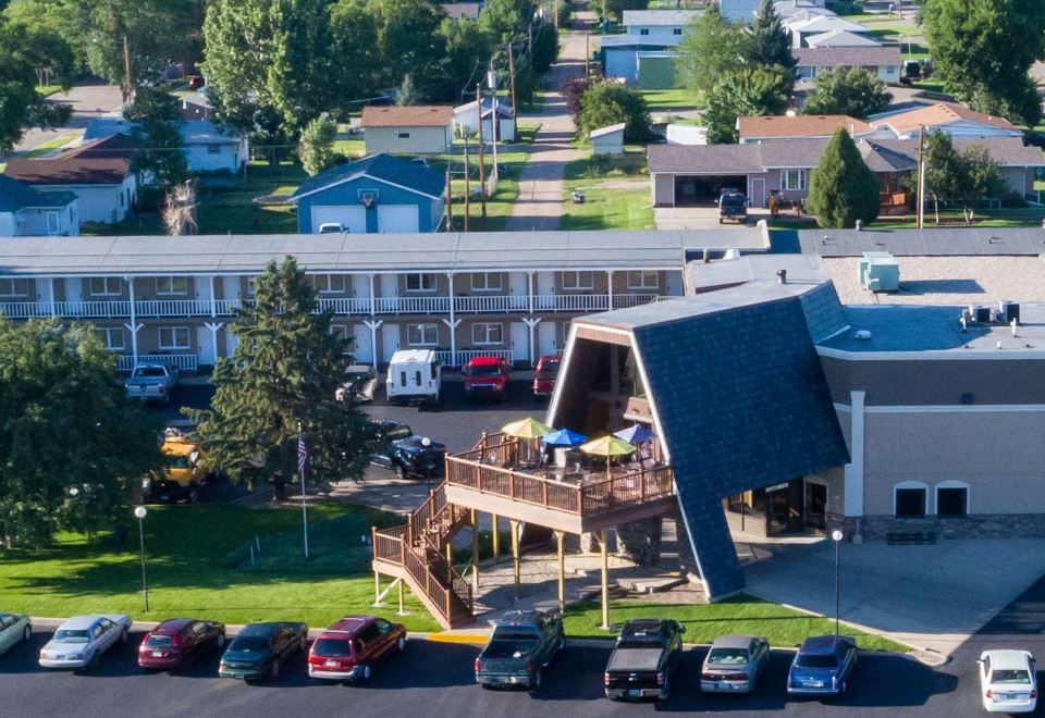 aerial view of a motel surrounded by cars and buildings , with people sitting on a porch at Wrangler Inn Mobridge