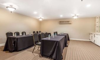 a large conference room with several rows of chairs arranged in a semicircle , facing a long table at The Aurora Inn Hotel and Event Center