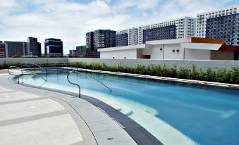 a modern swimming pool with a curved edge , surrounded by buildings and trees , under a cloudy sky at Hotel 101 Manila