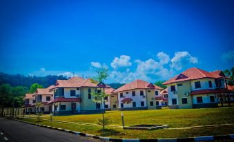 a row of multi - story houses with red roofs , situated on a grassy field under a blue sky at Kertih Damansara Inn