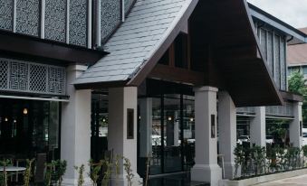 a modern building with a black roof and white walls , located in a residential area at Diamond Park Inn Chiangrai & Resort