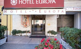 "a hotel entrance with a sign that reads "" hotel europa "" above the door , and a red flower bed in front of the building" at Hotel Europa