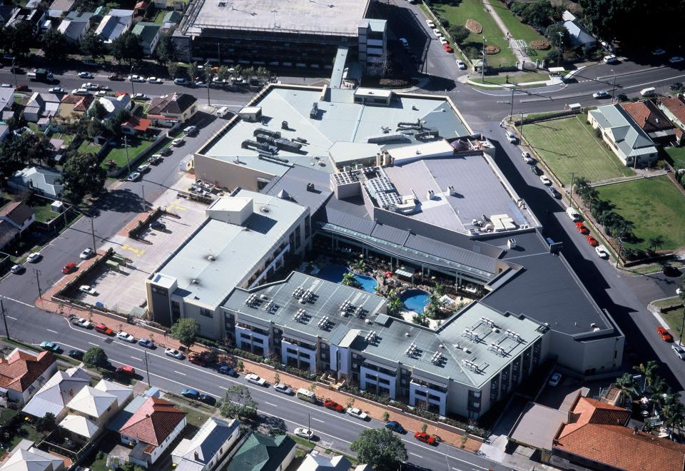 aerial view of a large commercial building with multiple parking lots , swimming pools , and buildings surrounding it at The Executive Inn, Newcastle
