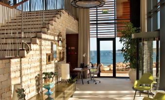 a spacious , well - lit living room with stone walls and a large window overlooking the ocean at Martinhal Sagres Beach Family Resort Hotel