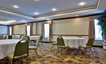 a well - lit conference room with green chairs and white tablecloths , giving it an elegant and comfortable atmosphere at Spring Lake Inn & Suites - Fayetteville